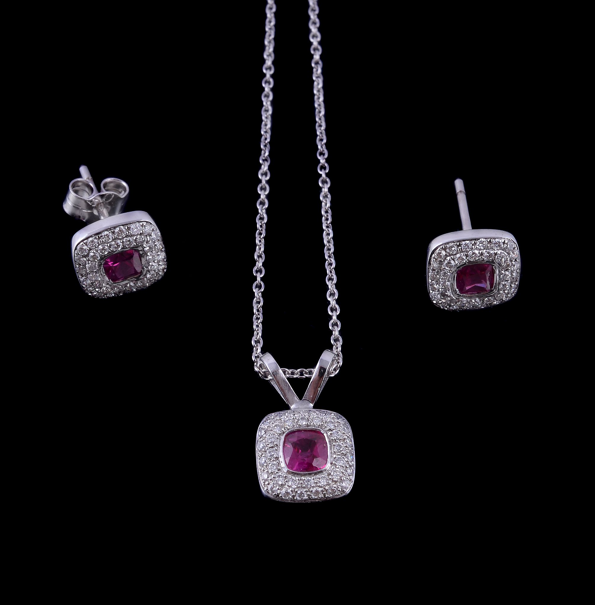 A ruby and diamond pendant, the cushion cut ruby collet set within a surround of brilliant cut