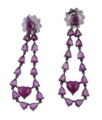 A pair of ruby earrings, the drops set with a heart shaped cabochon ruby suspended within a