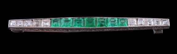 A 1920s emerald and diamond bar brooch, the millegrain channel set graduated step cut emeralds to