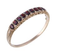 A garnet and diamond hinged bangle, set with oval cut garnets and eight cut diamonds, approximately
