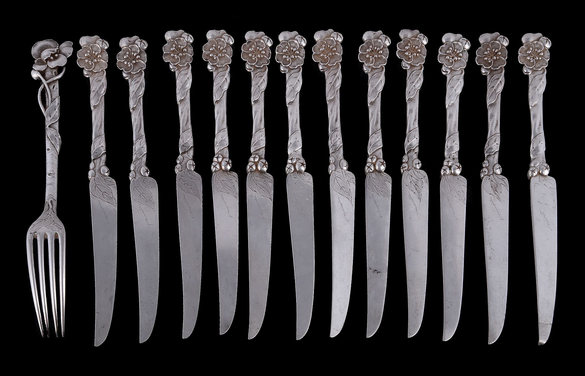 A set of twelve Art Nouveau silver fruit knives and one fork, unmarked, the knife blades with