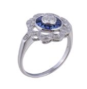 A diamond and sapphire cluster ring , the central brilliant cut diamond within a surround of