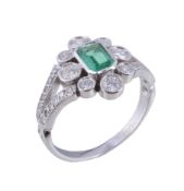 An emerald and diamond cluster ring, the step cut emerald with canted corners within a flower head