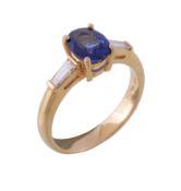 A sapphire and diamond three stone ring, the central oval cut sapphire between two tapered baguette