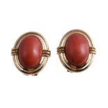 Ω A pair of coral earrings, the oval cabochon coral within a polished surround, with post fittings,