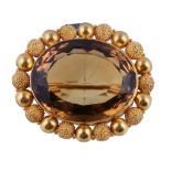 A mid Victorian citrine brooch, circa 1860, the oval cut citrine within a textured and polished