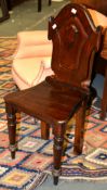 A mahogany hall chair, first half 19th century, the shaped shield back with central cartouche