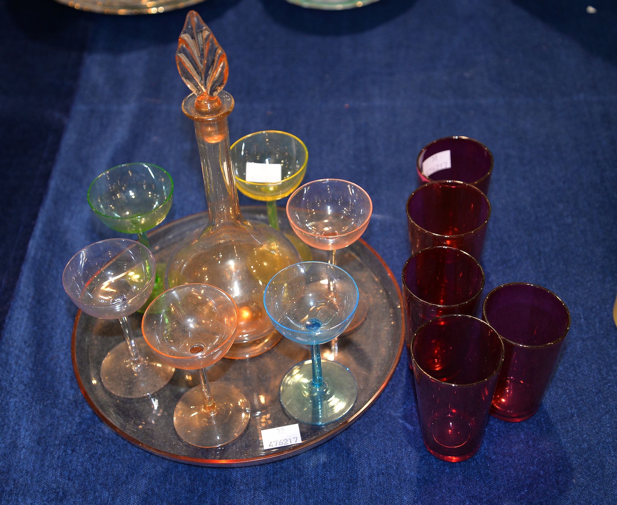 A coloured glass liqueur set, and five cranberry tinted glass beakers