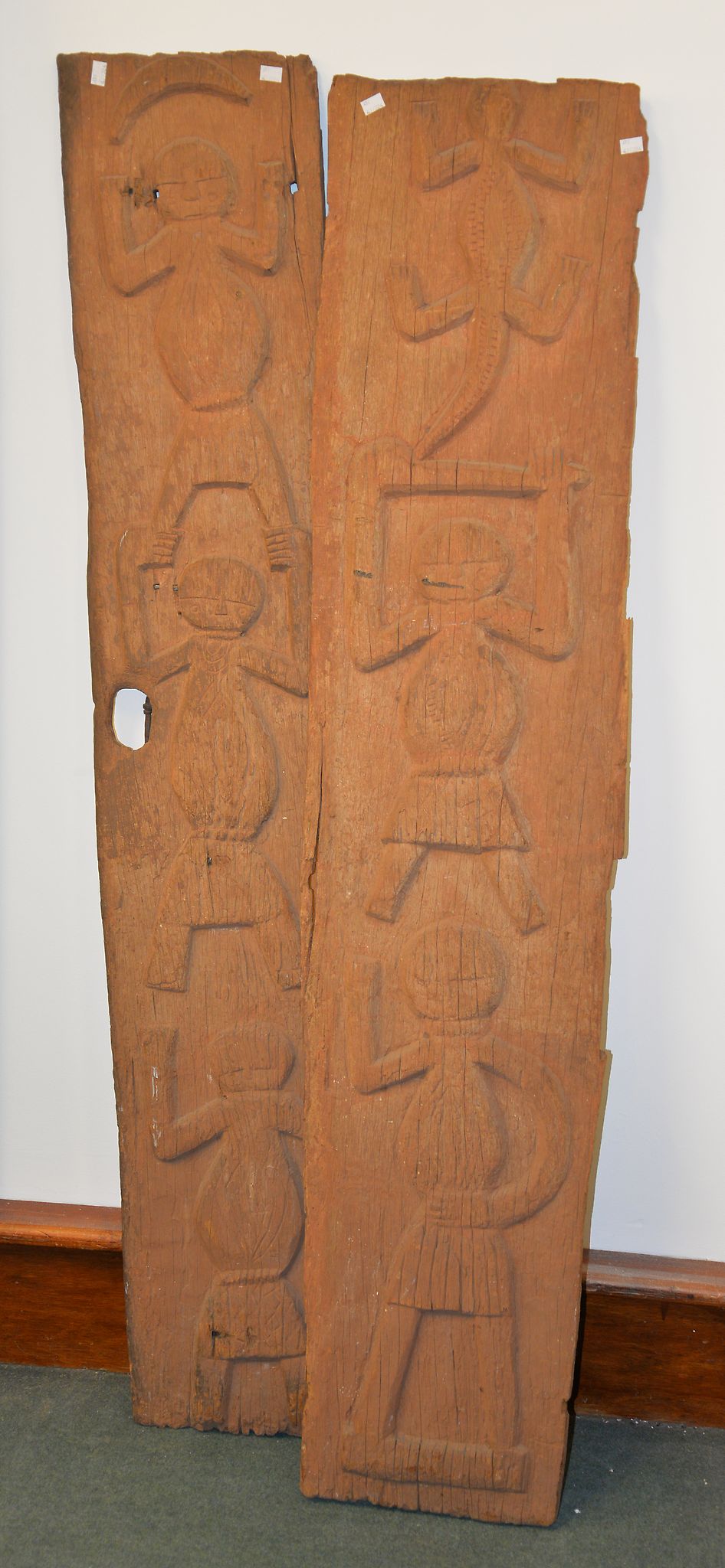 Two wooden carved panels in the manner of Aboriginal examples, depicting figures and animals, each