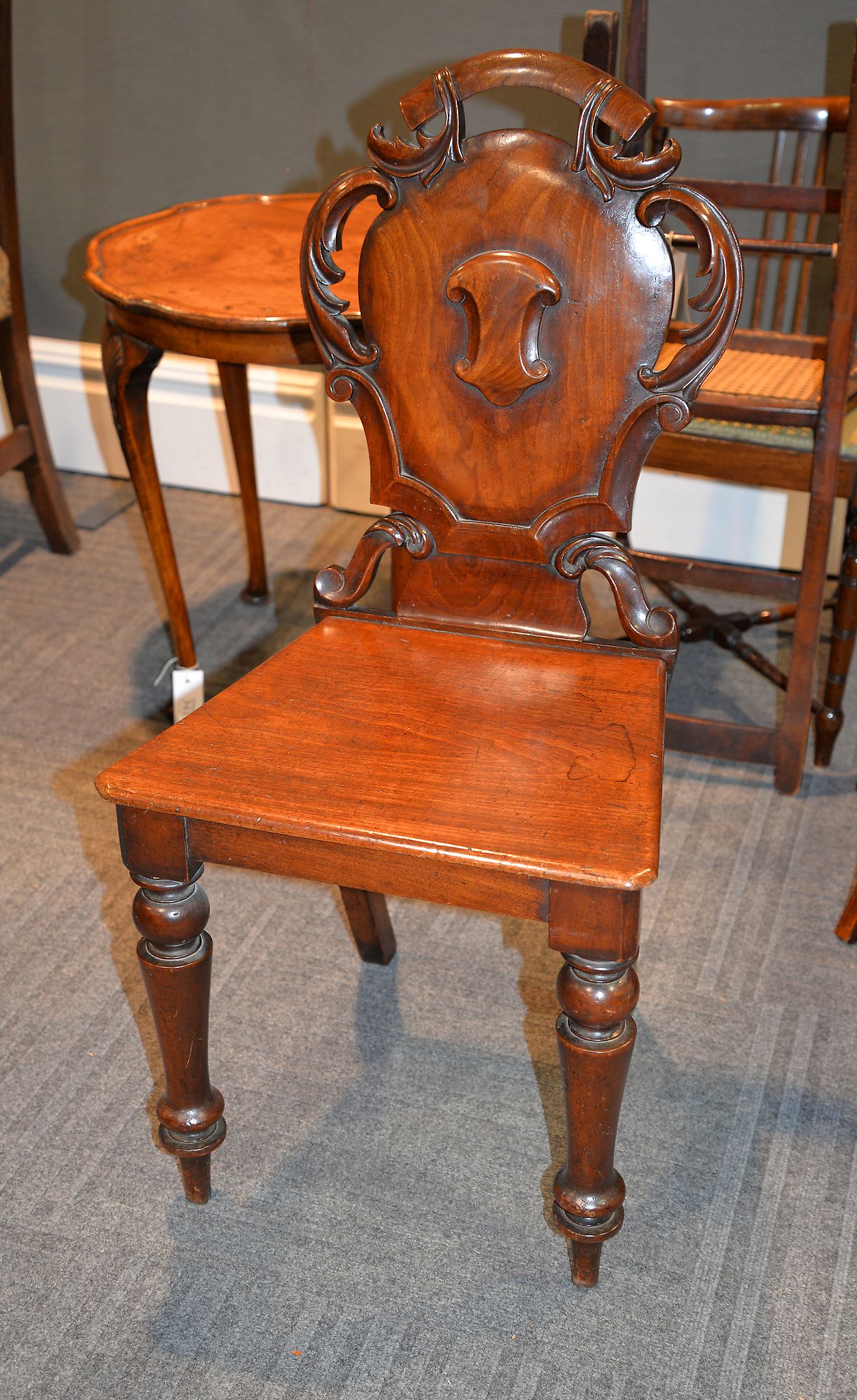 A Victorian mahogany hall chair, with pierced acanthus scrolls surrounding the shield back with