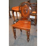 A Victorian mahogany hall chair, with pierced acanthus scrolls surrounding the shield back with