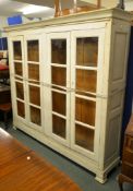 A white painted bookcase, the two banks of shelves behind two pairs of glazed doors, 190cm high