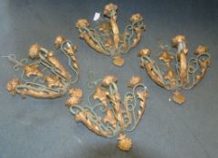 A set of four wrought iron three light wall appliques, painted in green and gilt with fleur-de-lys