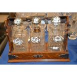 An oak and silver plate mounted three-bottle tantalus, various bottles, each with associated china