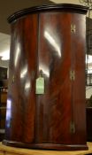 A George III mahogany corner cupboard, with two drawers enclosing shelves, 103cm high