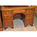 A walnut and mahogany banded kneehole desk, in George III style, the quarter book-matched top