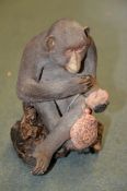 A Japanese Pottery Model of A Macaque, the simian sits cross-legged whilst holding a kinchaku and