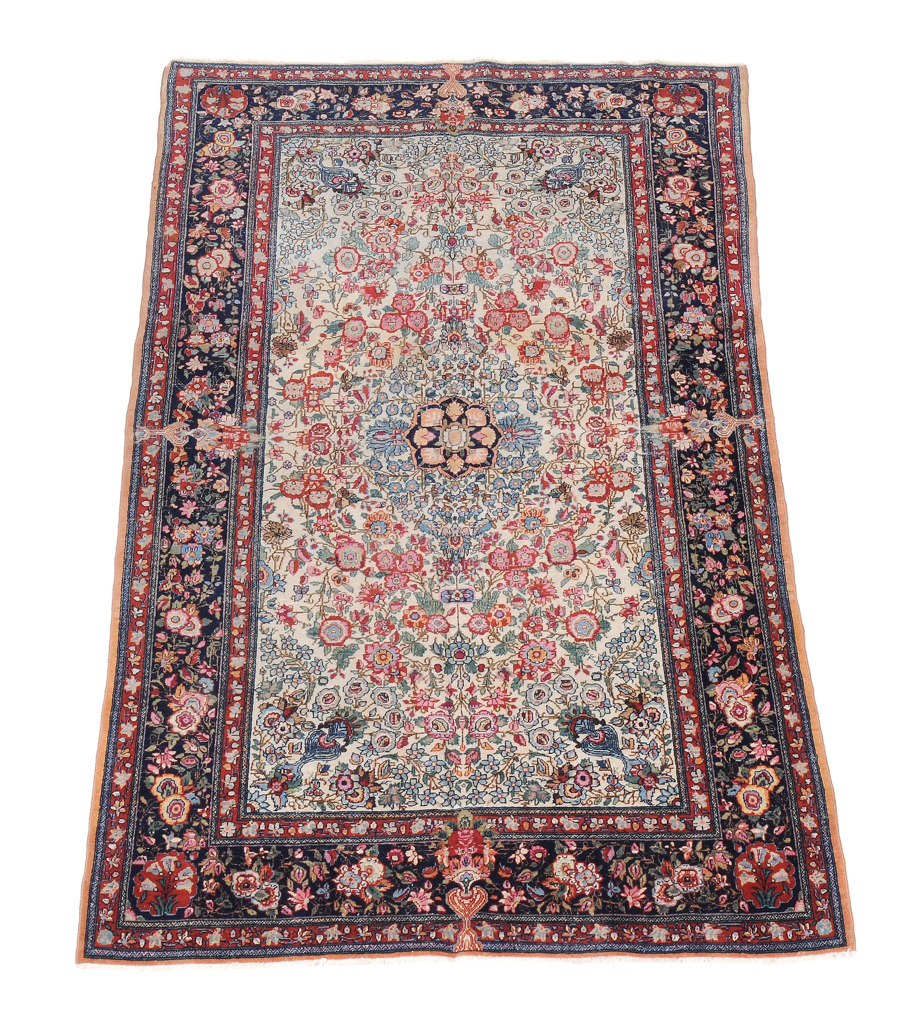 A Kashan rug, the cream and sky blue field decorated profusely with red and polychrome flowers,