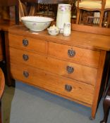An oak chest of drawers with two short and two long drawers each with a decorative copper pull