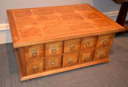 A modern mixed wood parquetry coffee table, the base with an arrangement of drawers to each opposing