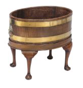 A George III mahogany oval and brassbound wine cooler, circa 1780, now as a jardinière, with lions