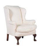 A carved beech and upholstered wing armchair, in George II style, 20th century, the shaped