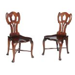 A pair of George II mahogany hall chairs, circa 1750, each cartouche shaped back decorated with