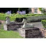 A pair of stone composition models of recumbent horses, each depicted with head raised with a