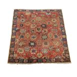 A Teftez carpet, the red field decorated overall with large stylised flowerheads, in navy orange