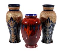 A pair of Royal Doulton Lambeth stoneware vases , modelled in relief with panels of stiff-leaf