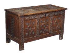 An oak coffer , the associated four panel lid above an earlier carved three panel base, 73cm high,