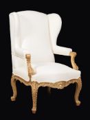 A carved giltwood wing armchair in Louis XV style , 20th century, upholstered in plain calico,