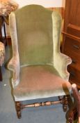 A walnut wing armchair, in 18th century style, early 20th century, in green velvet upholstery