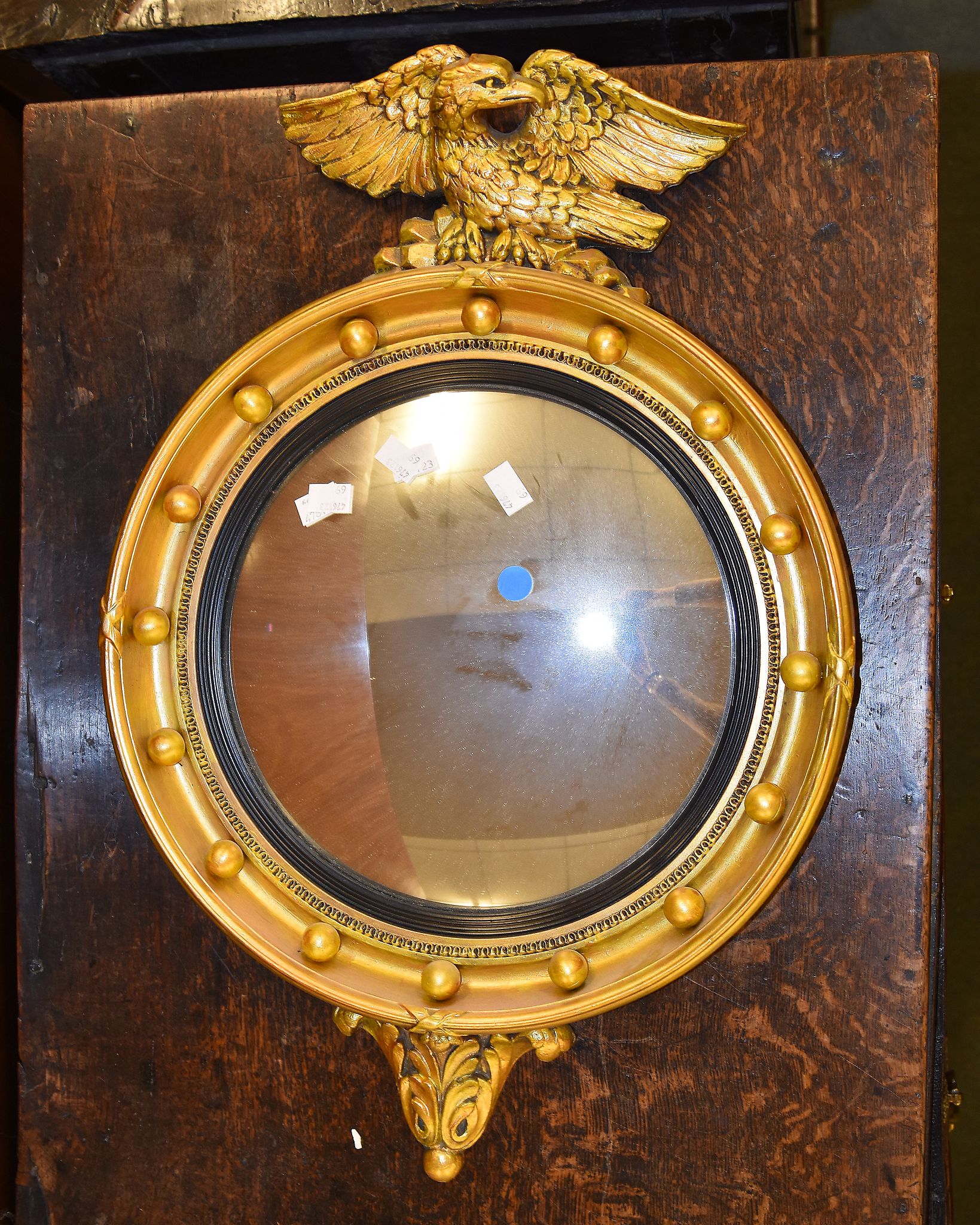 A giltwood mirror in Regency style, the convex plate surmounted by an eagle, 64cm high overall