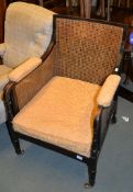 A stained beech bergÃ¨re armchair in Regency style, with caned back and sides