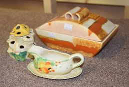 A Clarice Cliff Sungay Bizarre flower holder, a Wilkinson Honeyglaze sauce-boat and stand, and a