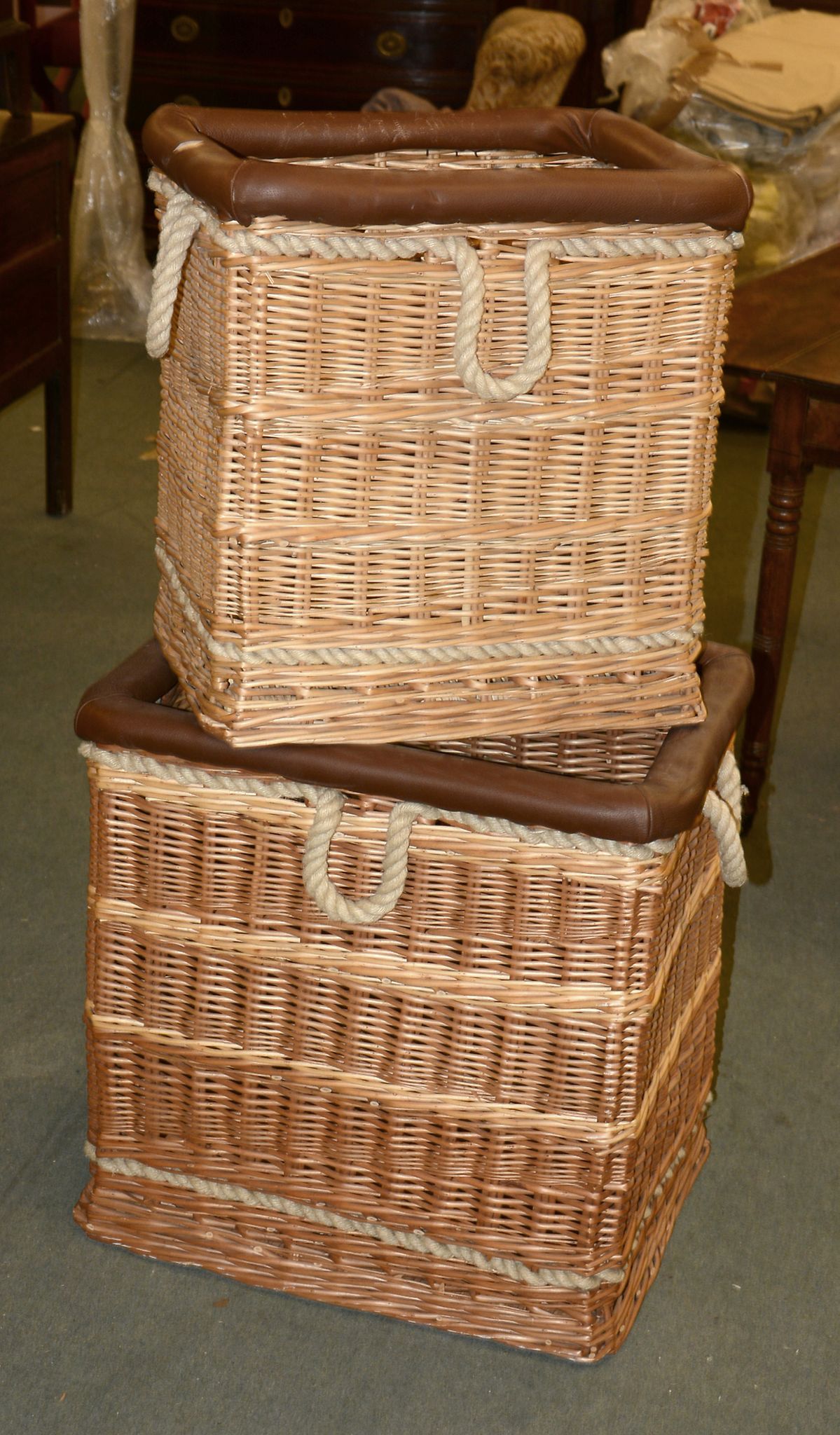 Two wicker, leatherette, and rope mounted log baskets, the larger 61cm high