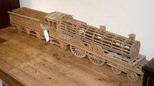 A pierced wooden model of a train pulling a tender