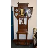 An Arts and Crafts oak hall stand, early 20th century, with various hooks and mirror above