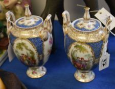 A pair of Dresden two handles urns and covers, each decorated with Watteauesque panels, 22cm high