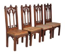 A set of four Victorian Gothic Revival oak side chairs, each with lancet arched backs, above moulded