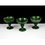 Three carved hardstone liqueor glasses in nephrite jade, the shallow circular bowls atop knopped