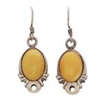 A pair of amber drop earrings in sterling silver, each set with an oval amber cabochon.