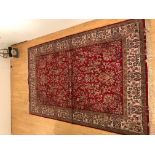 A large antique Indian carpet / rug with floral patterns against a red ground 305x195cm approx