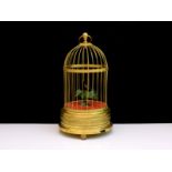 A singing bird automaton designed as a vari-coloured feathered bird in a gilt metal cage, which