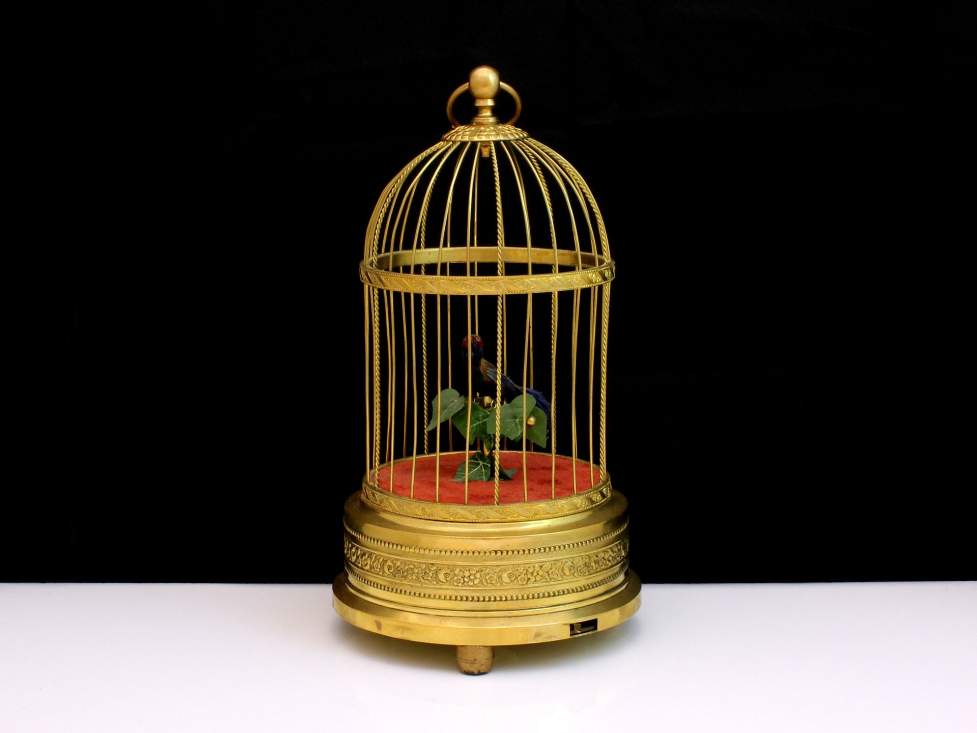 A singing bird automaton designed as a vari-coloured feathered bird in a gilt metal cage, which