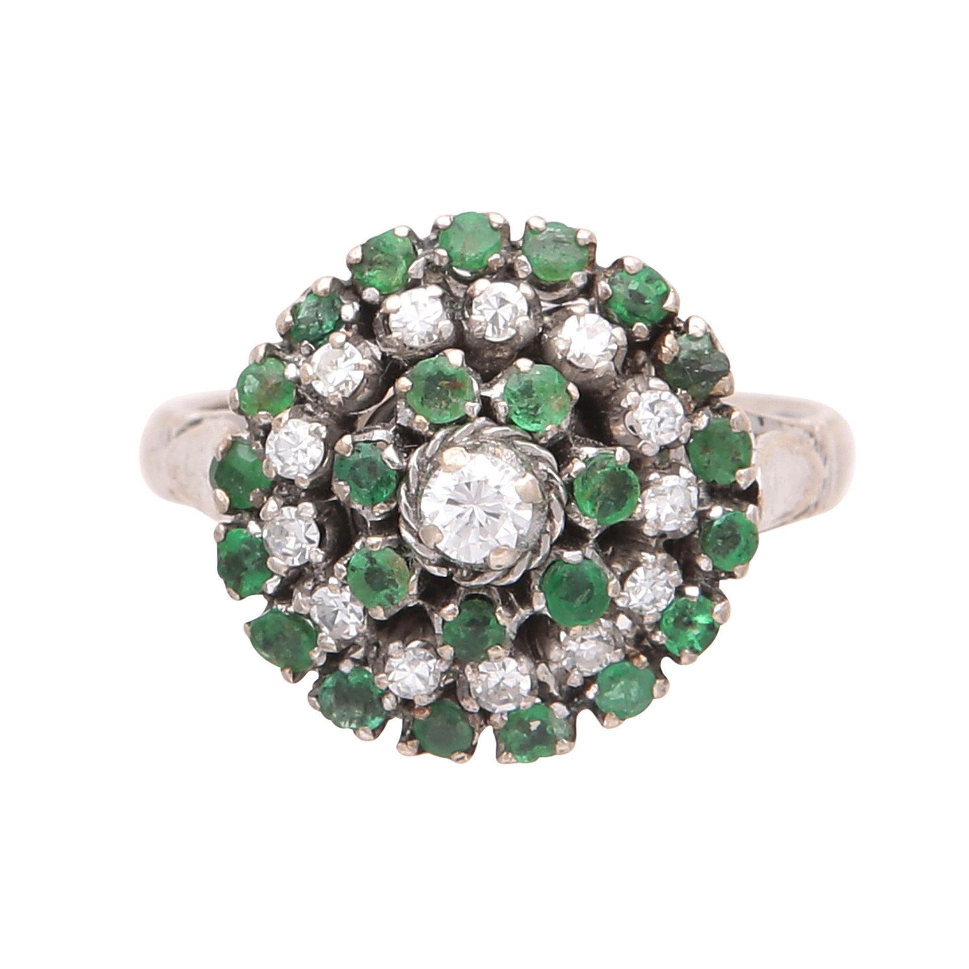 An emerald and diamond cluster ring in yellow gold, designed as a central round cut diamond