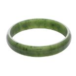 A nephrite jade bangle of circular form with a bevelled edge, carved from green nephrite jade.