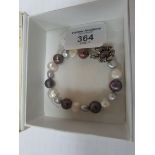 Silver string bracelet of multi-coloured pearls