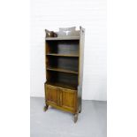 An oak Arts & crafts bookcase with three fixed shelves over a pair of panelled cupboard doors to the